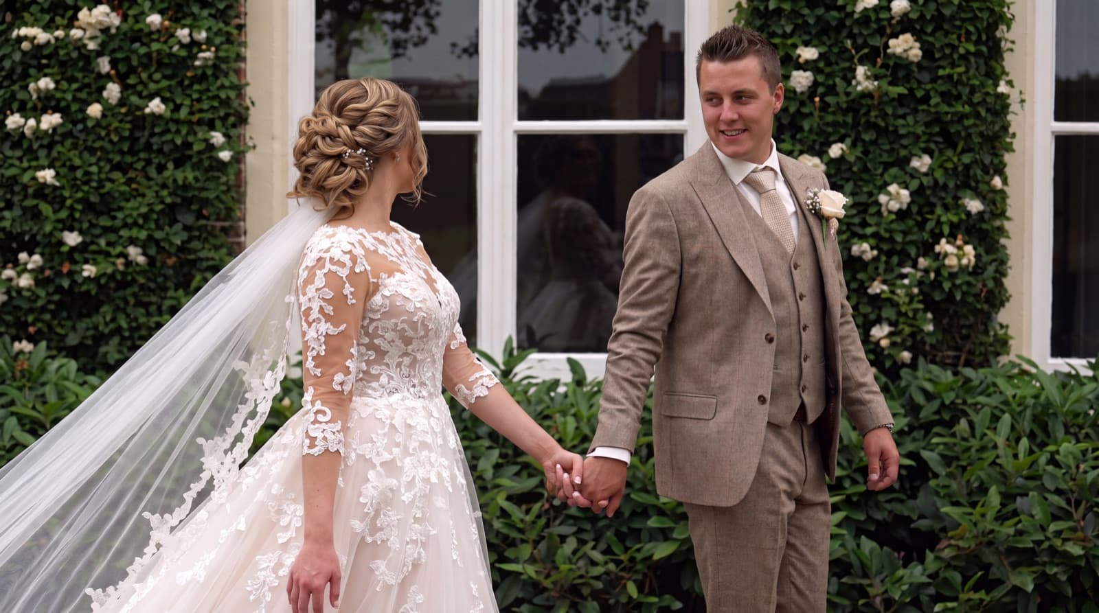 Bruidspaar hand in hand voor een romantische tuin
